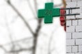 Urban pharmacy or drug store sign, led display green cross on the wall in the city street, copy space Royalty Free Stock Photo