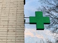 Urban pharmacy or drug store sign, led display green cross on the wall in the city street, copy space Royalty Free Stock Photo