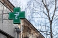 Urban pharmacy or drug store sign, led display green cross on the wall in the city street, copy space Royalty Free Stock Photo