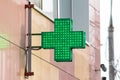 Urban pharmacy or drug store sign, led display green cross on the wall in the city street Royalty Free Stock Photo