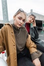 Urban portrait of beautiful young women with leather jacket and sweater in black jeans sits and poses on the street Royalty Free Stock Photo