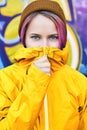 Urban portrait cool young woman in yellow jacket and knitted hat posing against wall painted with graffiti. Royalty Free Stock Photo