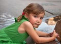 An urban portrait of a little girl near the granitic parapet wall of a fountain