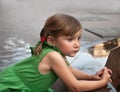 An urban portrait of a little girl near the granitic parapet wall of a fountain