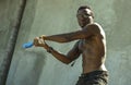 Urban portrait of young aggressive and upset violent black African American man using baseball bat threatening at grunge corner in