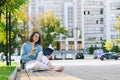 Urban portrait of young business woman in eye glasses, t- shirt, trousers is walking in the city street. Drinking healthy drink Royalty Free Stock Photo