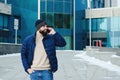 Urban portrait of young elegant business man in winter casual clothes, jacket, hat. Walking in the city street, talking on phone Royalty Free Stock Photo
