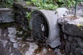 urban river: water oozes out of a round pipe, blocked by an old grate