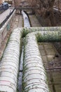 Urban stream. Industrial pipes. Concrete riverbed and river bank