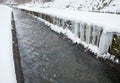 Urban stream in winter. Icicles on the riverbanks Royalty Free Stock Photo