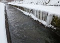 Urban stream in winter. Icicles on the riverbanks Royalty Free Stock Photo