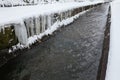 Urban stream in winter. Icicles on the riverbanks Royalty Free Stock Photo