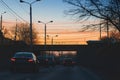 Urban street, bridge, cars and lampposts on the background of the romantic sunset