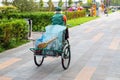 Urban street cleaner riding bicycle with garbage bag through municipal park on sunny day. Sweeper worker with bicycle on pavement Royalty Free Stock Photo