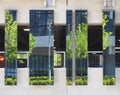 Urban street scene with modern office building and trees reflected in mirrored surfaces on a car park structure Royalty Free Stock Photo