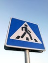 Urban street sign pedestrian crossing in front of blue sky