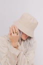 Urban street style Blonde. Details of everyday look. Casual beige outfit and accessories. Bucket hat, chain and rings. Trendy