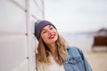 Pretty blond woman wearing knitted hat enjoys freedom, cool hipster girl in the city against a whitewall, street fashion Royalty Free Stock Photo