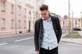 Urban stylish young guy with trendy hairstyle in fashionable elegant clothes near vintage houses outdoors. Business guy travels