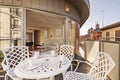 Urban terrace with a white circular outdoor table with a set of breakfast cups, access to a living room with a white sofa and a