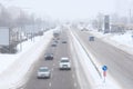Urban traffic in winter. Cars driving on a snowy road, a blizzard, poor visibility Royalty Free Stock Photo