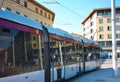 An urban tram runs through the chaos of city streets to bring commuters to their destination