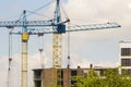 Urban view of silhouettes of two high industrial tower cranes working at construction of new brick building with workers in hard Royalty Free Stock Photo