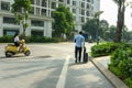 Urban walking road among green tree in modern apartment buildings in big city, with a man walk pulling luggage