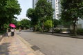 Urban walking road among green tree in modern apartment buildings in big city. People walking on the path