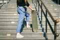 Urban woman with skate. Hipster girl with skateboard in city. Extreme sport and emotions concept. Alternative lifestyle. Stylish Royalty Free Stock Photo