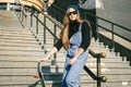 Urban woman with skate. Hipster girl with skateboard in city. Extreme sport and emotions concept. Alternative lifestyle. Stylish Royalty Free Stock Photo