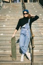 Urban woman with skate. Hipster girl with skateboard in city. Extreme sport and emotions concept. Alternative lifestyle. Stylish Royalty Free Stock Photo