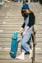 Urban woman with skate. Hipster girl with skateboard in city. Extreme sport and emotions concept. Alternative lifestyle. Stylish Royalty Free Stock Photo