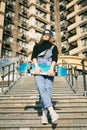 Urban woman with skate. Hipster girl with skateboard in city. Extreme sport and emotions concept. Alternative lifestyle. Stylish Royalty Free Stock Photo