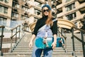 Urban woman with skate. Hipster girl with skateboard in city. Extreme sport and emotions concept. Alternative lifestyle. Stylish Royalty Free Stock Photo