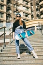 Urban woman with skate. Hipster girl with skateboard in city. Extreme sport and emotions concept. Alternative lifestyle. Stylish Royalty Free Stock Photo