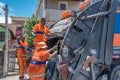 The urban workers from the municipal COMLURB putting waste into recycling garbage truck