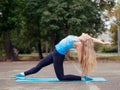 Urban yoga outdoor in summer. Caucasian blond girl of medium build doing training in the urban park, selected focus