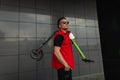 Urban young man hipster in trendy sunglasses in stylish summer jeans clothes posing with a scooter near a modern building. Royalty Free Stock Photo