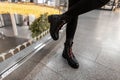 Urban young woman in a vintage black leather boots with red shoelaces in fashion jeans poses in a store. Close up of female legs Royalty Free Stock Photo