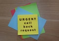 Urgent call back request text on colorful notepad on wooden background