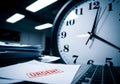 Urgent deadline approaching with documents piled high beside a large clock in a modern office setting Royalty Free Stock Photo