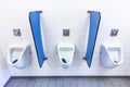 Urinals for men on white wall with blue partitions