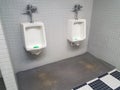 Urinals on wall in bathroom with grey and black and white tiles Royalty Free Stock Photo