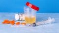 Urine container, syringe and colored pills Royalty Free Stock Photo