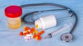 Urine container, syringe, phonedoscope and colored pills on blu Royalty Free Stock Photo