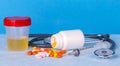 Urine container, syringe, phonedoscope and colored pills Royalty Free Stock Photo