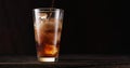 Uring the liquid into the cola glass full of ice cubes. Isolated on dark background Royalty Free Stock Photo