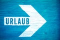 Urlaub in German language, Holiday or Vacation text sign written on a white directional arrow on a blue wooden signboard Royalty Free Stock Photo