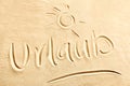 Urlaub text with shining sun on beach sand Royalty Free Stock Photo